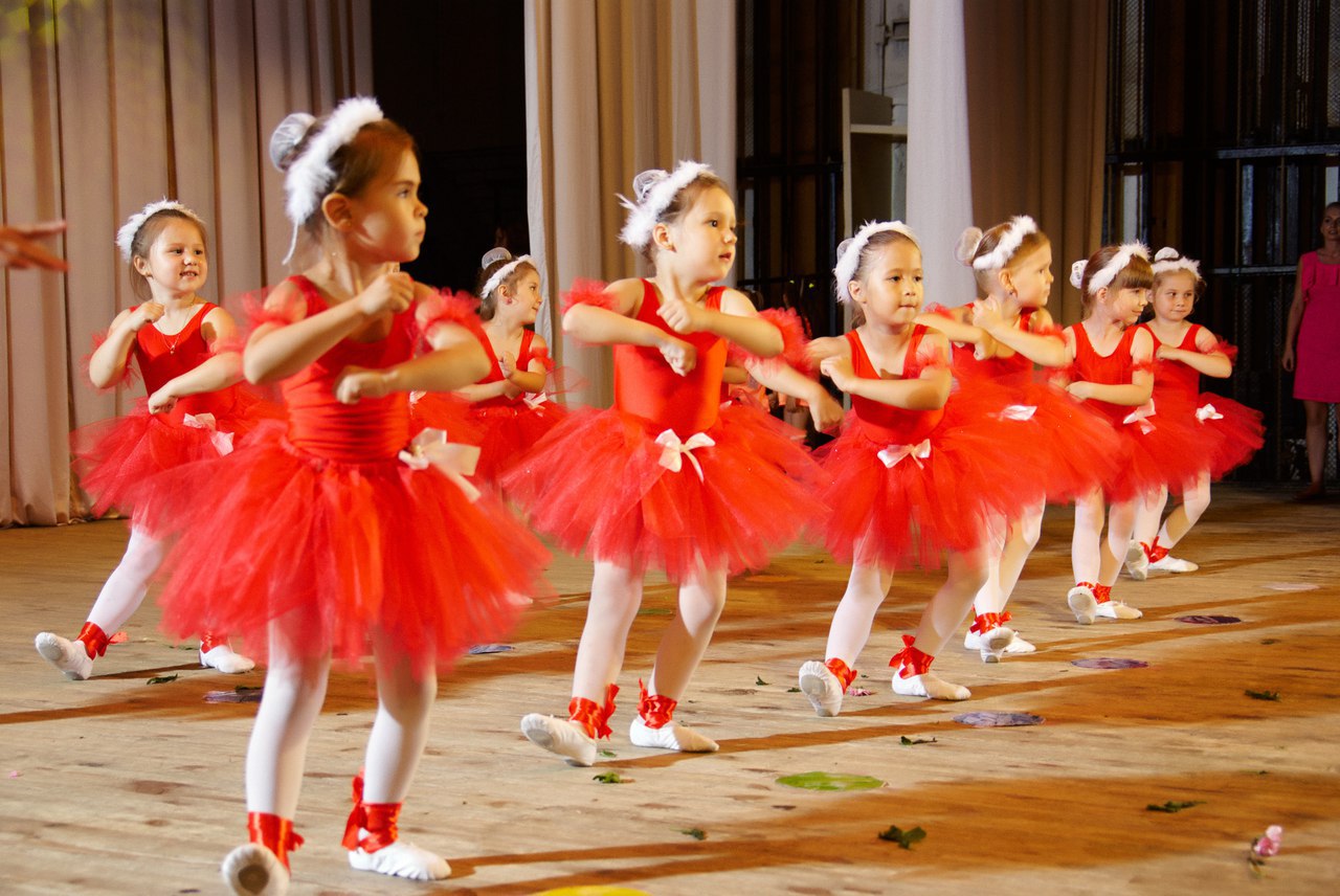 Девочки танцуют на сцене в красных платьях и белых колготках (фото)